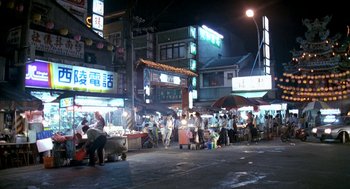 Movie still from “Rebels of the Neon God” (1992), directed by Tsai Ming-liang – A group of people standing on the side of a road; Extreme Wide shot, High angle