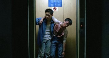 Movie still from “Rebels of the Neon God” (1992), directed by Tsai Ming-liang – Two young men standing next to each other in an elevator; Medium shot, Low angle