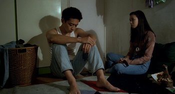 Movie still from “Rebels of the Neon God” (1992), directed by Tsai Ming-liang – A man sitting on the floor next to a woman holding a nintendo wii controller; Medium shot, High angle