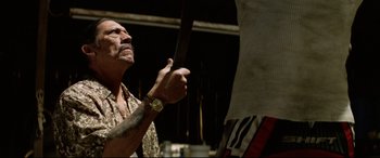 Movie still from “xXx” (2002), directed by Rob Cohen – An older man holding a knife up to his face; Medium shot, Low angle