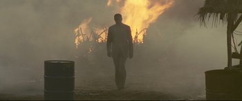 Movie still from “xXx” (2002), directed by Rob Cohen – A man in a suit walking through a field of fire; Wide shot, Low angle