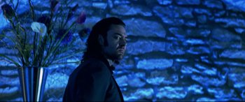 Movie still from “xXx” (2002), directed by Rob Cohen – A man standing in front of a brick wall in front of a projection screen; Medium shot, Low angle