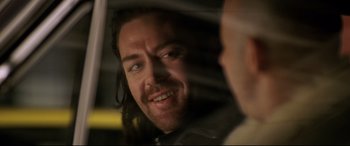 Movie still from “xXx” (2002), directed by Rob Cohen – A person with long black hair; Close Up shot, Over the shoulder angle