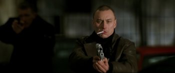 Movie still from “xXx” (2002), directed by Rob Cohen – A man smoking a cigarette while holding a gun in his hand; Close Up shot, Low angle