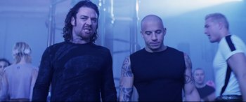 Movie still from “xXx” (2002), directed by Rob Cohen – Two men standing next to each other in front of a blue background; Medium shot, Low angle