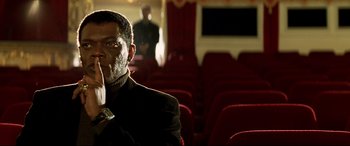 Movie still from “xXx” (2002), directed by Rob Cohen – A man sitting in an empty movie theater holding a cell phone; Close Up shot, Low angle