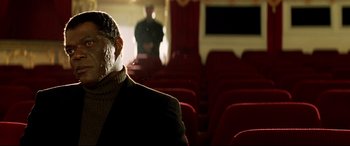 Movie still from “xXx” (2002), directed by Rob Cohen – A man sitting in an empty theater with red seats; Close Up shot, Low angle