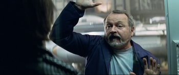 Movie still from “xXx” (2002), directed by Rob Cohen – An older man with a beard and a white shirt is waving; Close Up shot, Low angle