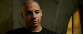 Movie still from “xXx” (2002), directed by Rob Cohen – A bald man with a black t - shirt is looking to his left; Close Up shot, Over the shoulder angle