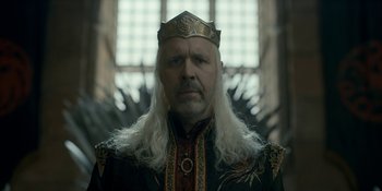 Movie still from “House of the Dragon” (2022), created by George R.R. Martin – A person wearing a crown near a window; Close Up shot, Low angle