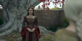 Movie still from “House of the Dragon” (2022), created by George R.R. Martin – A woman dressed in medieval clothing stands in front of a stone wall; Medium shot, Over the shoulder angle