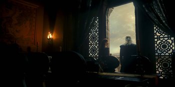 Movie still from “House of the Dragon” (2022), created by George R.R. Martin – Two people sitting on a balcony looking out at the sky; Wide shot, Low angle