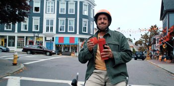 Movie still from “Hubie Halloween” (2020), directed by Steven Brill – A man on a scooter holding two cups; Medium shot, Low angle
