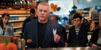 Movie still from “Hubie Halloween” (2020), directed by Steven Brill – A man in a suit holding a paper in his hand; Medium shot, Over the shoulder angle