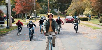 Movie still from “Hubie Halloween” (2020), directed by Steven Brill – A man riding a bike down the middle of a street; Wide shot, High angle