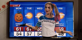 Movie still from “Hubie Halloween” (2020), directed by Steven Brill – A woman in a harley quinn costume standing in front of a sign; Medium shot, Over the shoulder angle