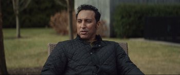 Movie still from “Human Capital” (2019), directed by Marc Meyers – A person sitting on a chair wearing a jacket; Close Up shot, Over the shoulder angle