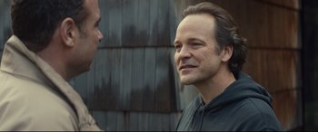 Movie still from “Human Capital” (2019), directed by Marc Meyers – A man standing next to another man in a black shirt; Close Up shot, Over the shoulder angle