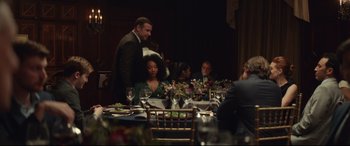 Movie still from “Human Capital” (2019), directed by Marc Meyers – A group of people sitting around a table; Medium shot, Over the shoulder angle