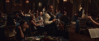 Movie still from “Human Capital” (2019), directed by Marc Meyers – A group of diners sitting at a table in front of a waiter; Wide shot, Over the shoulder angle