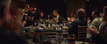 Movie still from “Human Capital” (2019), directed by Marc Meyers – A group of people sitting around a table; Wide shot, Over the shoulder angle