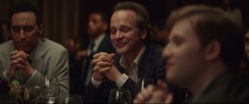 Movie still from “Human Capital” (2019), directed by Marc Meyers – A man sitting in front of a group of people; Close Up shot, Over the shoulder angle