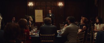 Movie still from “Human Capital” (2019), directed by Marc Meyers – A group of people sitting around a table; Wide shot, Over the shoulder angle