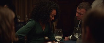 Movie still from “Human Capital” (2019), directed by Marc Meyers – A woman sitting at a table with a glass of wine; Medium shot, Over the shoulder angle