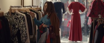 Movie still from “Human Capital” (2019), directed by Marc Meyers – A woman in a store holding onto a scarf; Medium shot, Over the shoulder angle