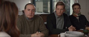 Movie still from “Human Capital” (2019), directed by Marc Meyers – Two men sitting at a table with a cup of coffee in front of them; Medium shot, Over the shoulder angle
