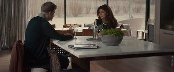 Movie still from “Human Capital” (2019), directed by Marc Meyers – A woman sitting at a table with a glass of wine; Medium shot, Over the shoulder angle