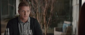 Movie still from “Human Capital” (2019), directed by Marc Meyers – A person sitting at a table holding a wine glass; Close Up shot, Over the shoulder angle