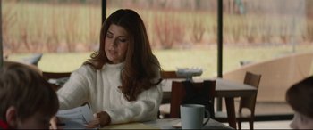 Movie still from “Human Capital” (2019), directed by Marc Meyers – A woman sitting at a table with a cup of coffee in front of her; Medium shot, Over the shoulder angle