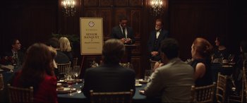 Movie still from “Human Capital” (2019), directed by Marc Meyers – A group of people sitting at a table with wine glasses; Wide shot, Over the shoulder angle