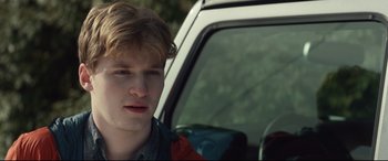 Movie still from “Human Capital” (2019), directed by Marc Meyers – A man sitting in the driver's seat of a white car; Close Up shot, Over the shoulder angle