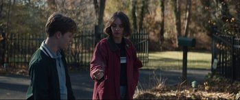 Movie still from “Human Capital” (2019), directed by Marc Meyers – A woman in a red coat is holding something in her hand; Medium shot, Over the shoulder angle