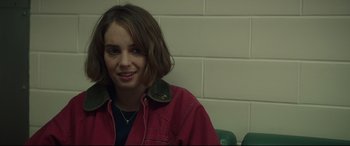 Movie still from “Human Capital” (2019), directed by Marc Meyers – A woman in a red jacket is smiling for the camera; Close Up shot, Over the shoulder angle