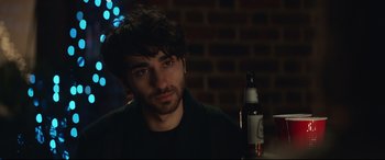 Movie still from “Human Capital” (2019), directed by Marc Meyers – A person sitting at a table with a bottle; Close Up shot, Over the shoulder angle