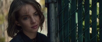 Movie still from “Human Capital” (2019), directed by Marc Meyers – A person near a metal fence; Close Up shot, Over the shoulder angle