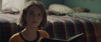 Movie still from “Human Capital” (2019), directed by Marc Meyers – A woman sitting in front of a bed reading a book; Close Up shot, Over the shoulder angle