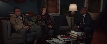 Movie still from “Human Capital” (2019), directed by Marc Meyers – A person sitting on a couch in a living room; Medium shot, Over the shoulder angle