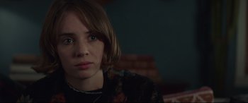 Movie still from “Human Capital” (2019), directed by Marc Meyers – A young woman sitting in front of a brick wall; Close Up shot, Over the shoulder angle