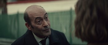 Movie still from “Human Capital” (2019), directed by Marc Meyers – An older man wearing a suit and a tie; Close Up shot, Over the shoulder angle