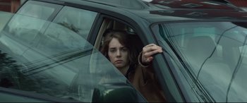 Movie still from “Human Capital” (2019), directed by Marc Meyers – A woman sitting in the driver's seat of a car; Close Up shot, Low angle
