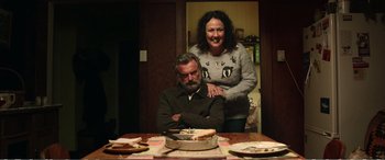 Movie still from “Hunt for the Wilderpeople” (2016), directed by Taika Waititi – A man and a woman sitting in front of a birthday cake; Medium shot, Over the shoulder angle