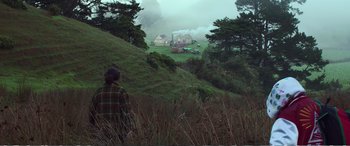Movie still from “Hunt for the Wilderpeople” (2016), directed by Taika Waititi – A man standing on a hill looking at a farm; Extreme Wide shot, High angle