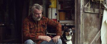 Movie still from “Hunt for the Wilderpeople” (2016), directed by Taika Waititi – A man sitting next to a brown and white dog; Medium shot, Over the shoulder angle