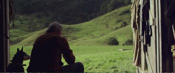 Movie still from “Hunt for the Wilderpeople” (2016), directed by Taika Waititi – An older man sitting in a grassy field; Wide shot, Over the shoulder angle