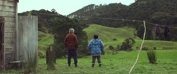 Movie still from “Hunt for the Wilderpeople” (2016), directed by Taika Waititi – Two people standing in a field looking at a sky line; Wide shot, Low angle