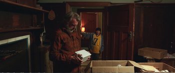 Movie still from “Hunt for the Wilderpeople” (2016), directed by Taika Waititi – A man standing next to another man holding a box; Medium shot, Over the shoulder angle